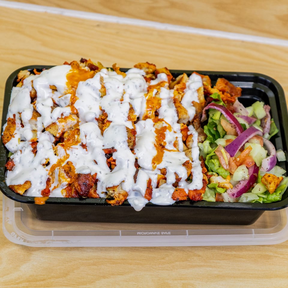 Halal chicken and rice platter with white sauce, orange sauce, and a side salad.